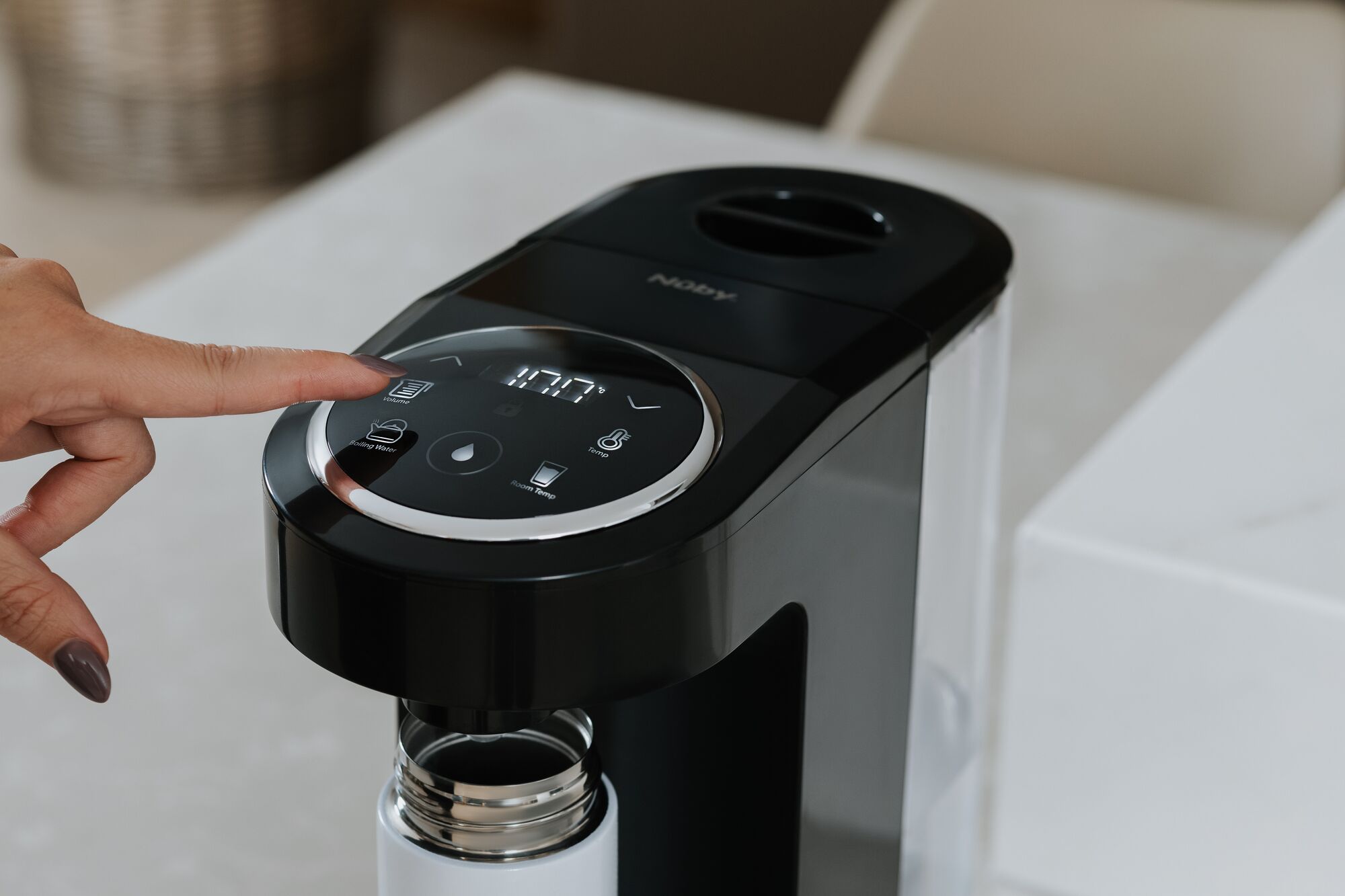 A finger pressing a button on a coffee machineDescription automatically generated