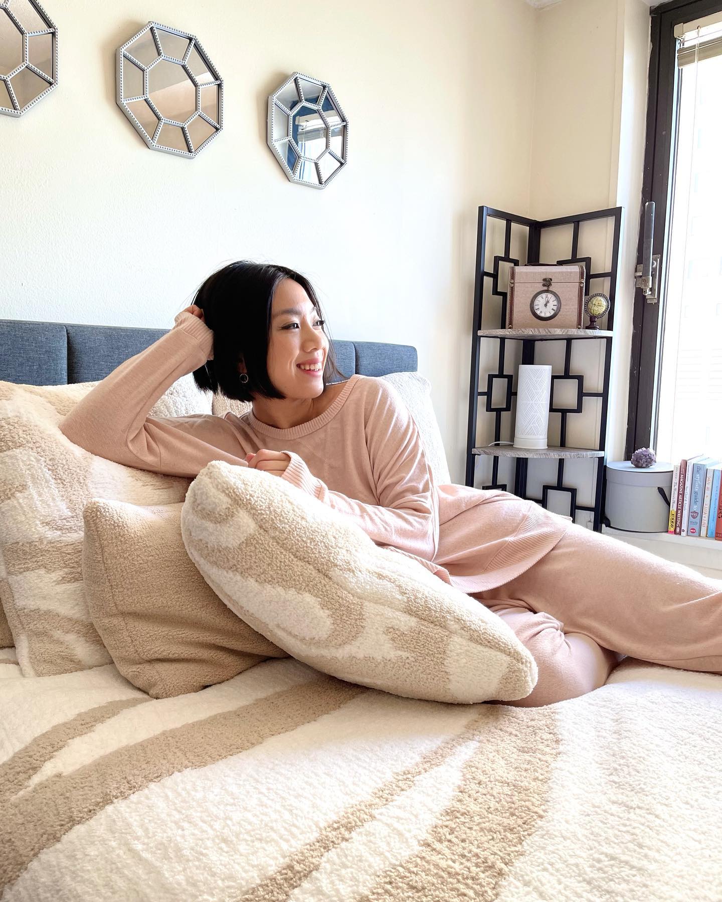 Woman smiling laying on bed. Woman lounging in loungewear. Woman lounging in pajamas. Woman smiling and relaxing on her bed.
