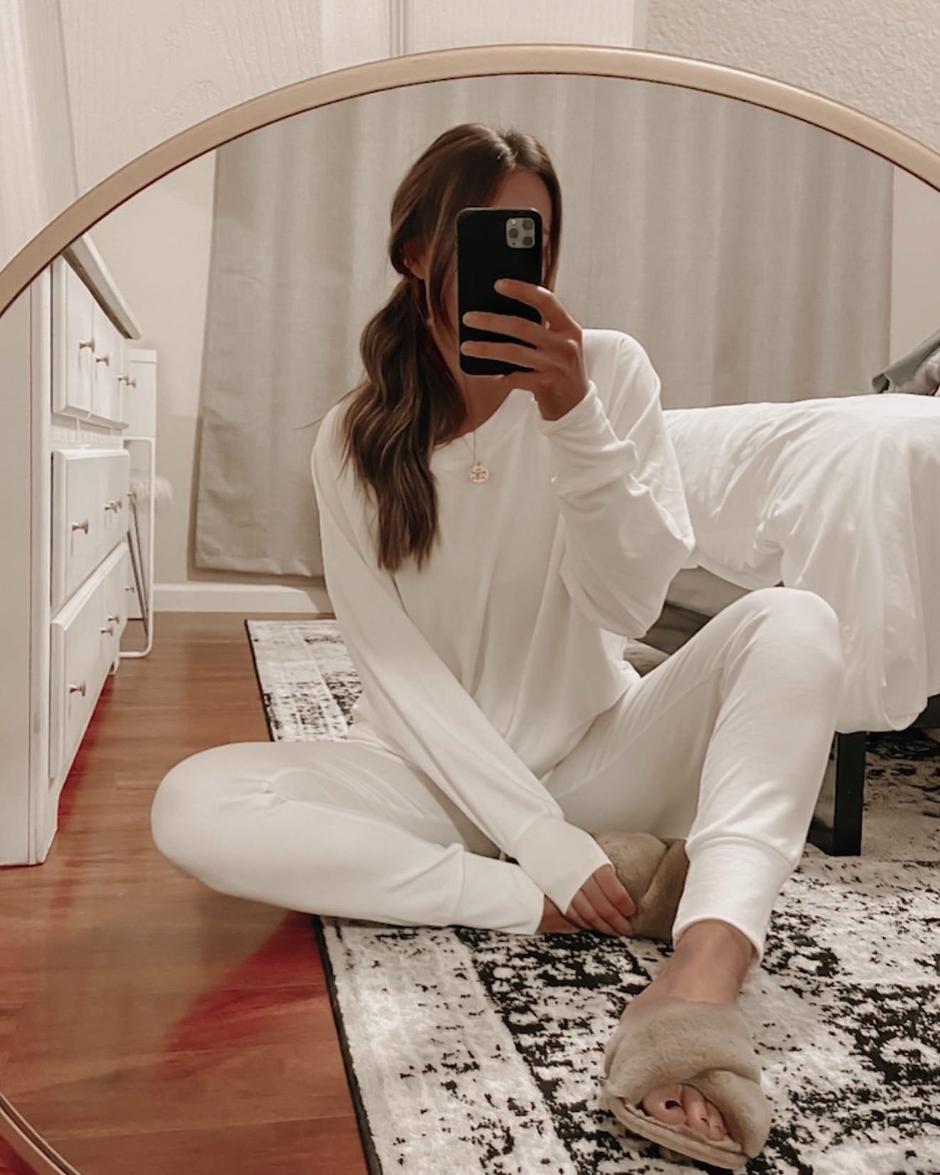 Woman taking a mirror selfie with loungewear on. Woman taking mirror pic. Woman wearing loungewear sitting on the floor.