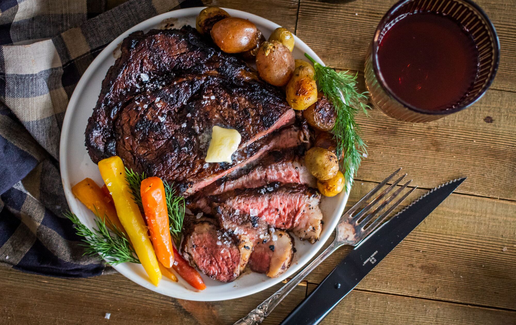 Grilled steak sliced on plate garnished with vegetables.