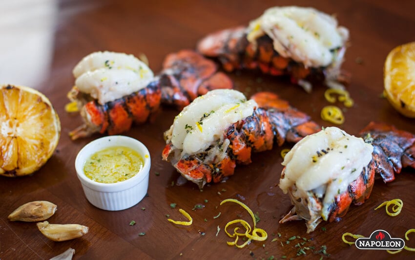 Grilling lobster tails served on table with roasted lemon slices. 