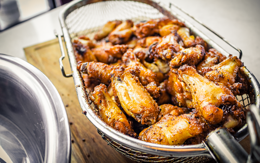 Grilling chicken wings inside rotisserie basket.